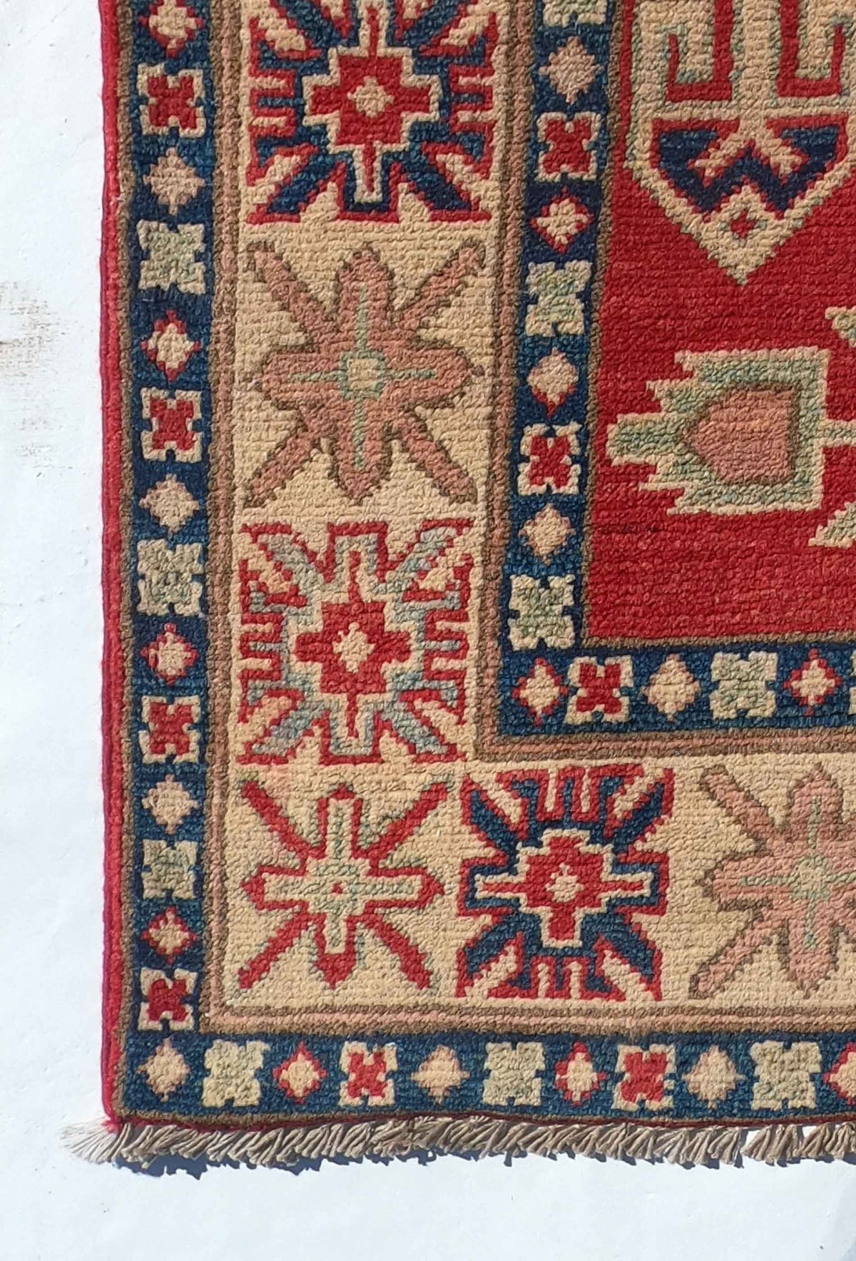 Alfombra Kazak de lana color rojo sobre piso de madera