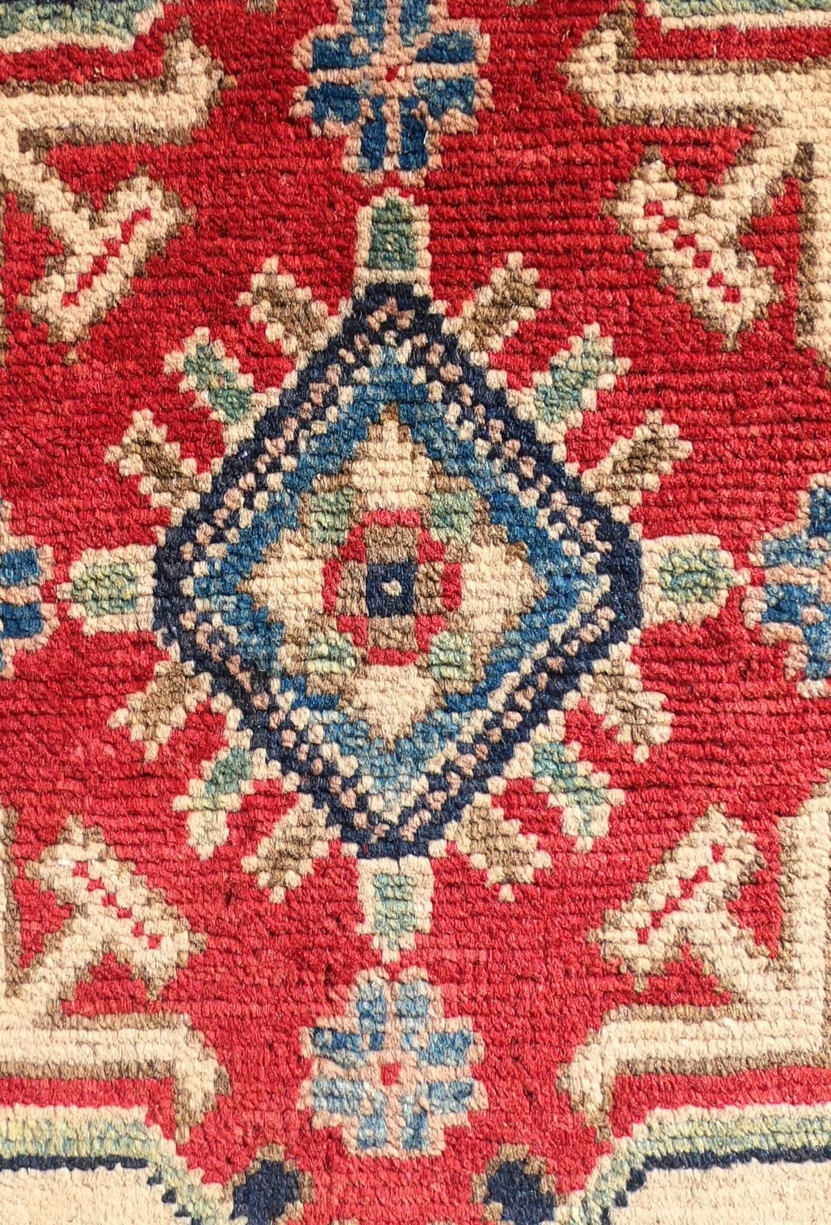Detalle del anudado a mano de la alfombra persa Kazak de lana.