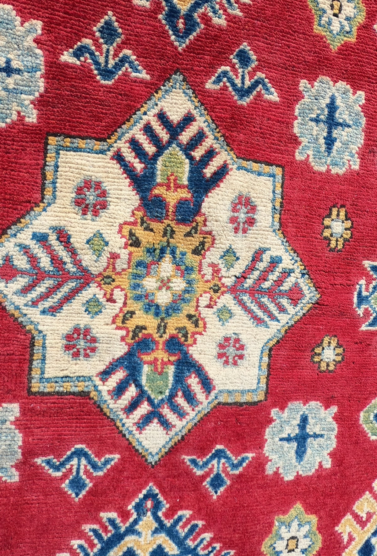 Detalle patrón geométrico en alfombra persa de lana, colores intensos y trama de algodón
