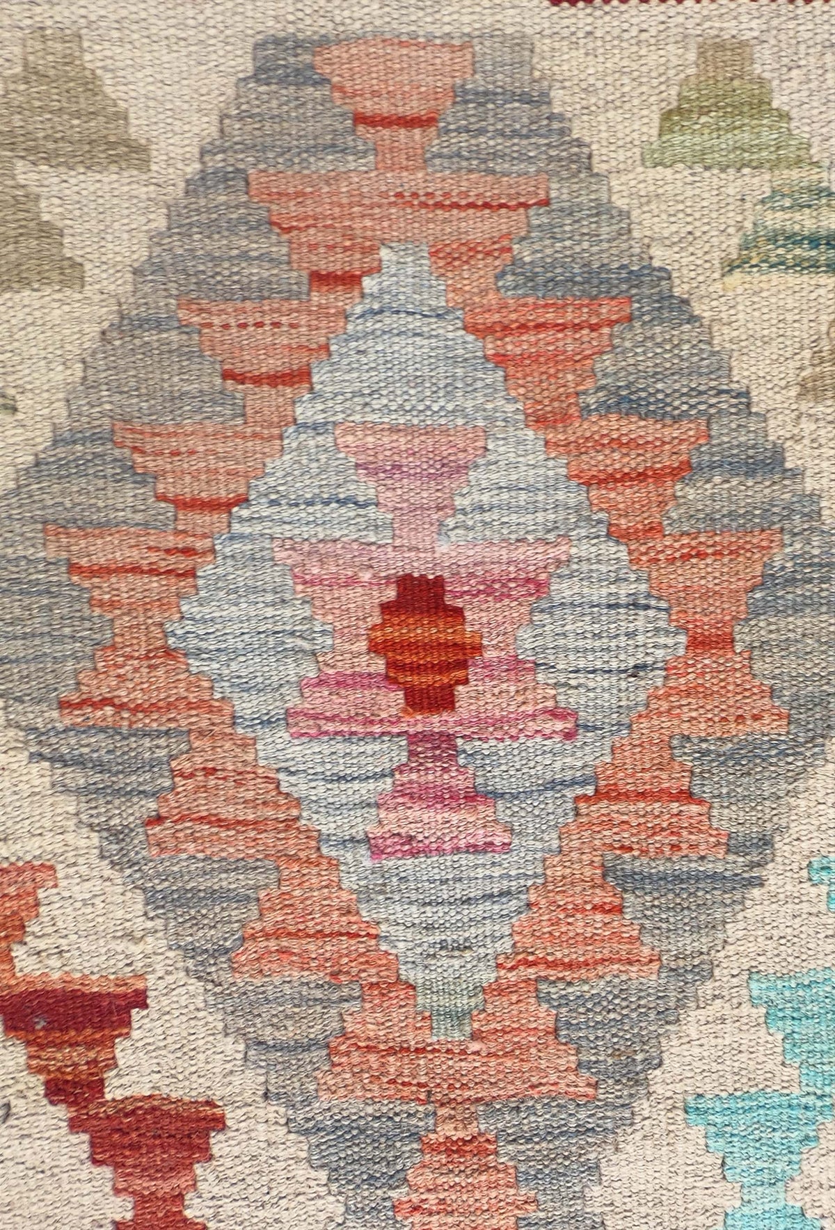 Detalle de motivos geométricos coloridos en alfombra Kelim de tejido plano