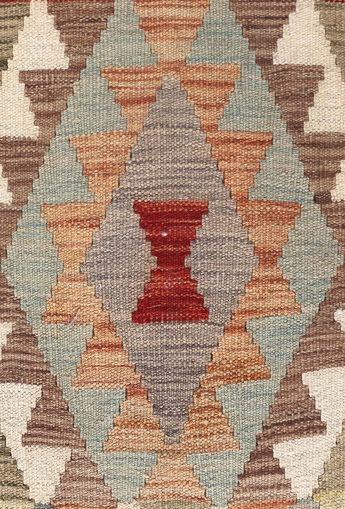 Detalle de motivos geométricos vibrantes en alfombra Kelim de tejido plano