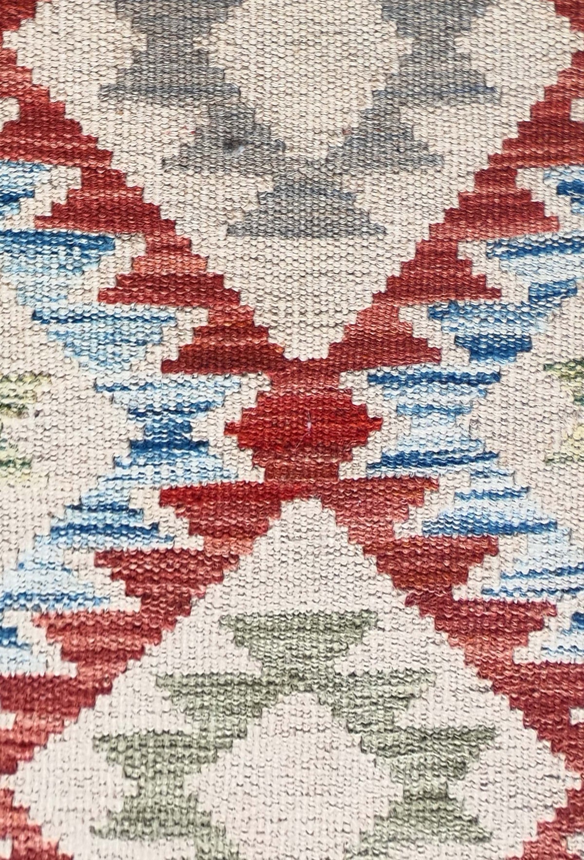 Detalle de motivos geométricos coloridos en alfombra Kelim de tejido plano