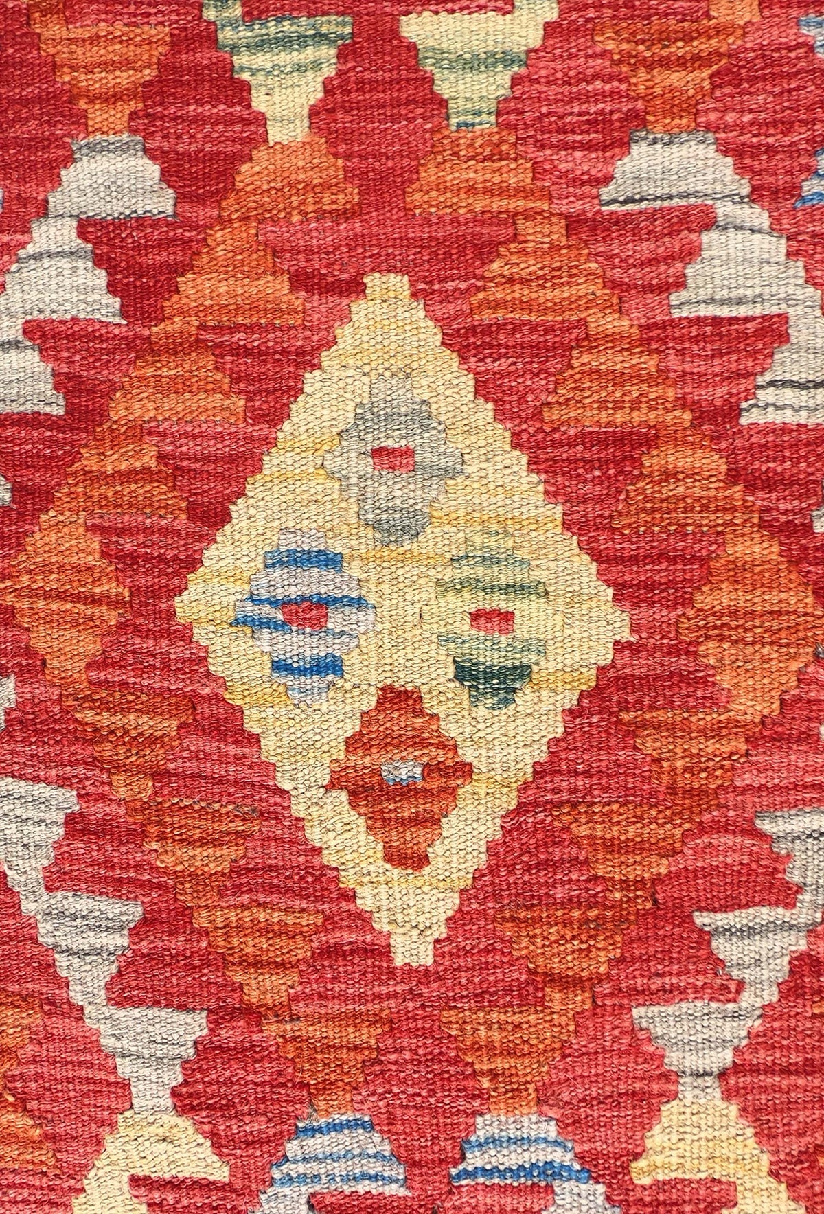 Detalle de motivos geométricos coloridos en alfombra Kelim de tejido plano