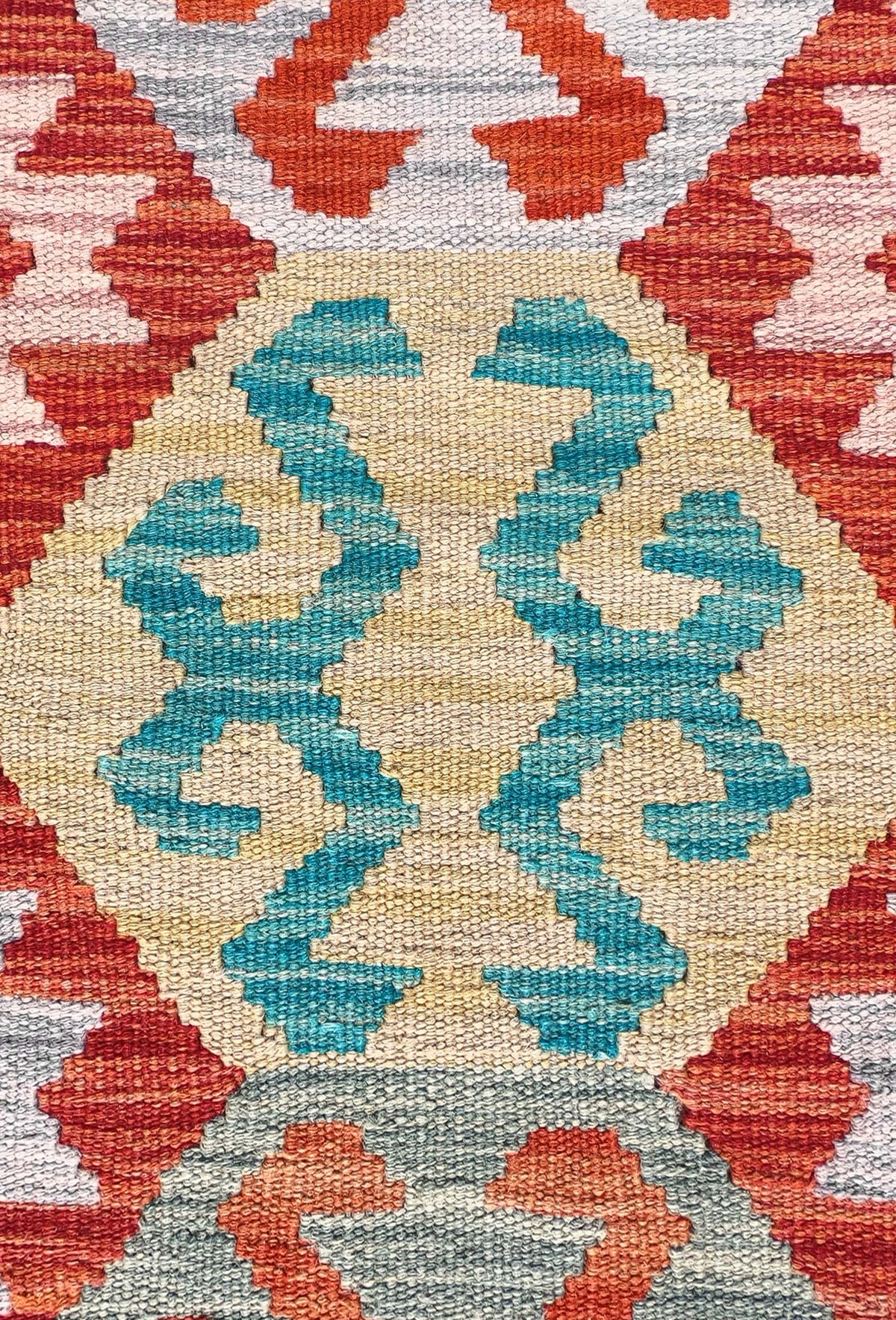 Detalle de motivos geométricos coloridos en alfombra Kelim de lana tejida