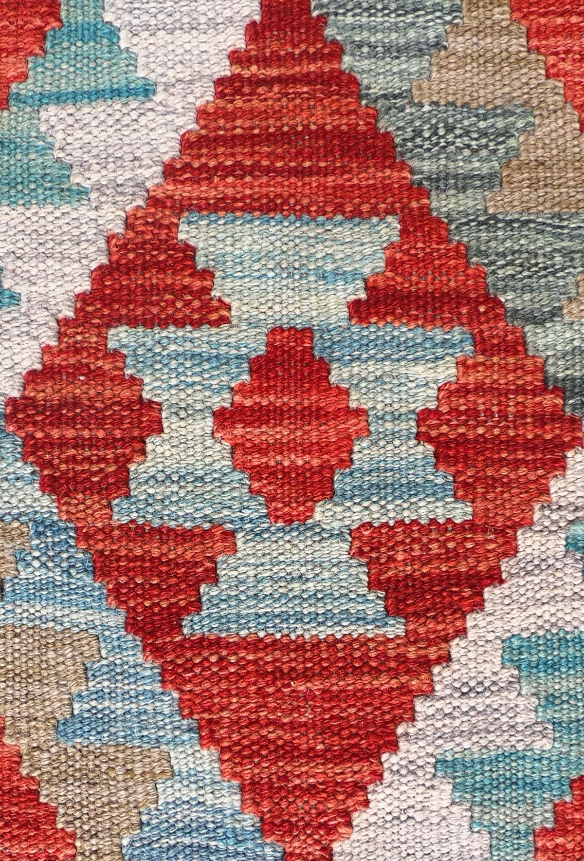 Detalle de motivos geométricos coloridos en alfombra Kelim de lana artesanal