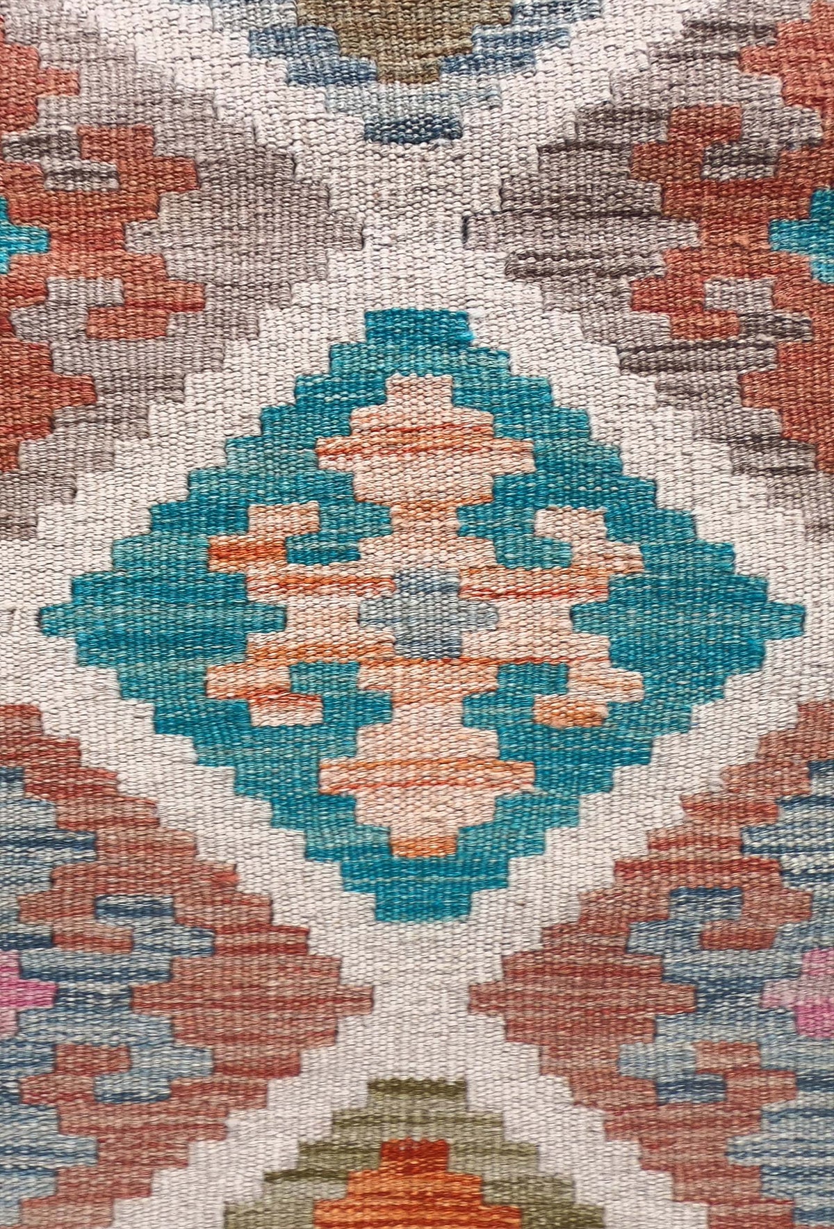 Detalle de motivos geométricos coloridos en alfombra Kelim de lana artesanal