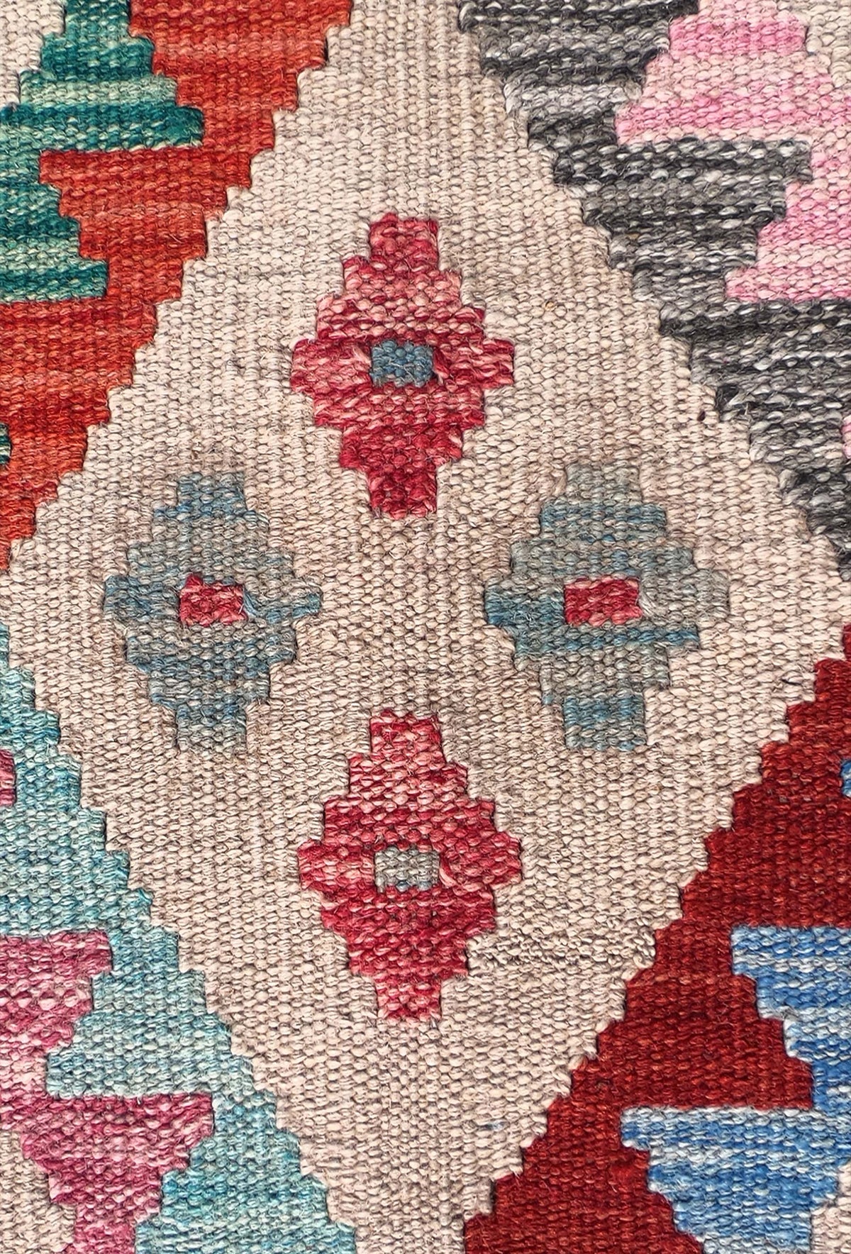 Detalle de motivos geométricos coloridos en alfombra Kelim de lana artesanal