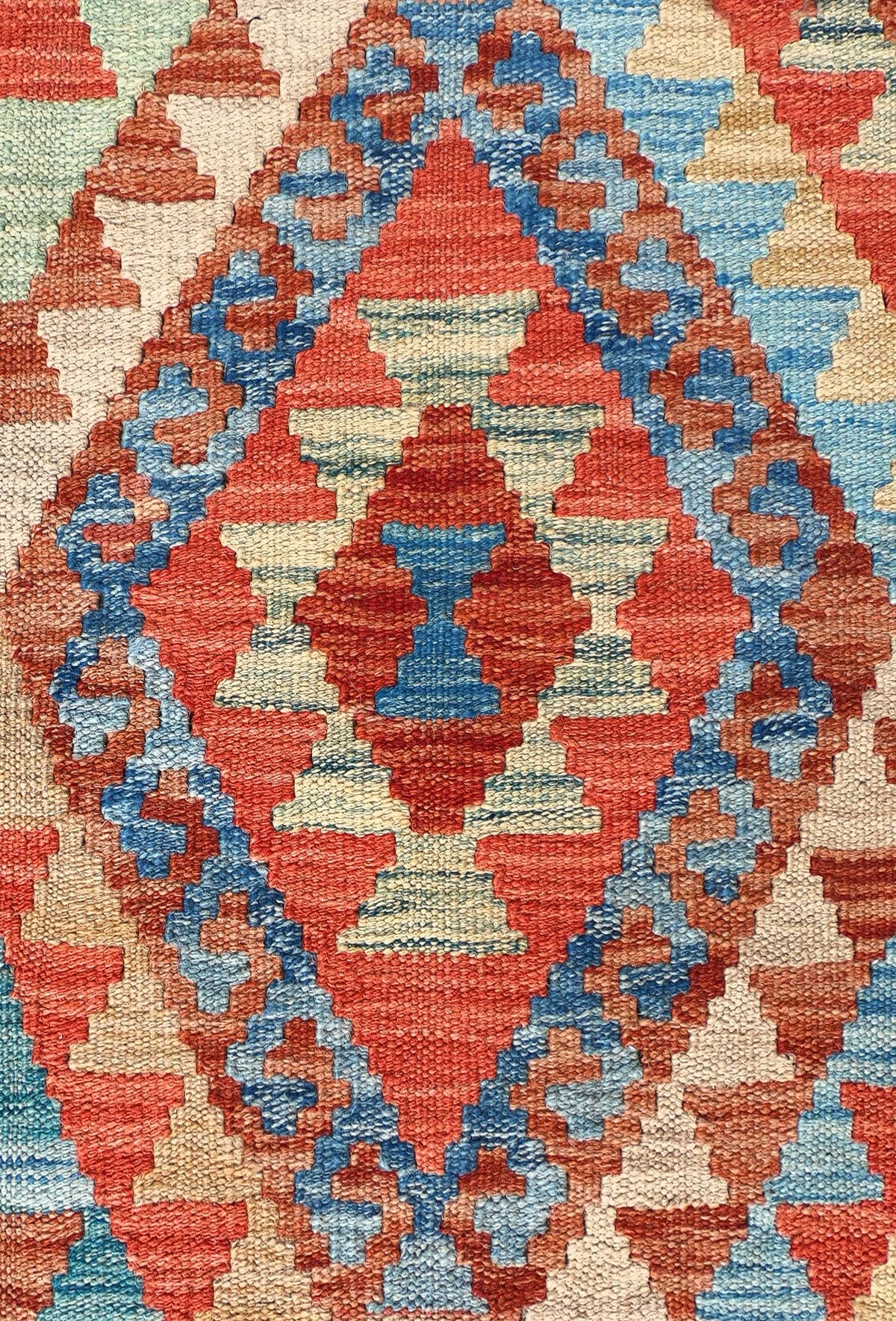 Detalle de motivos geométricos coloridos en alfombra Kelim de lana tejida en telar