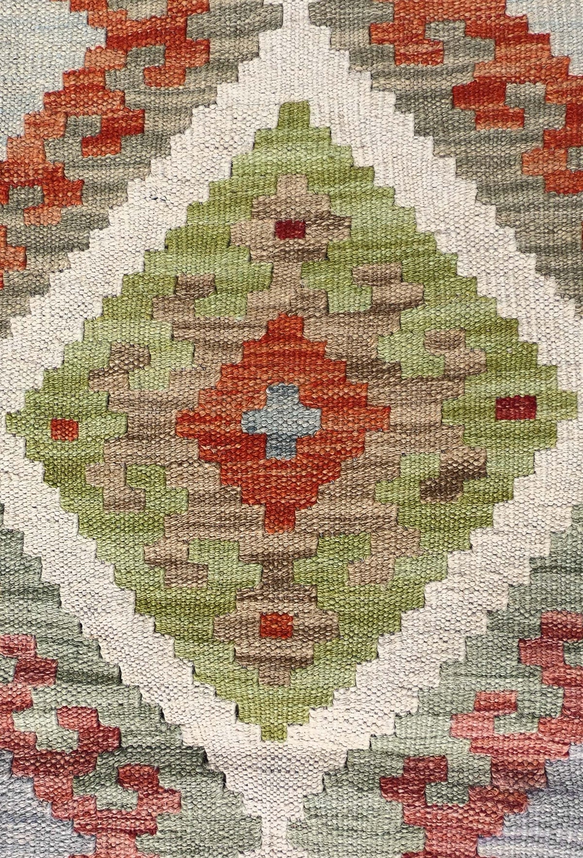 Detalle de motivos geométricos coloridos en alfombra Kelim de lana tejida