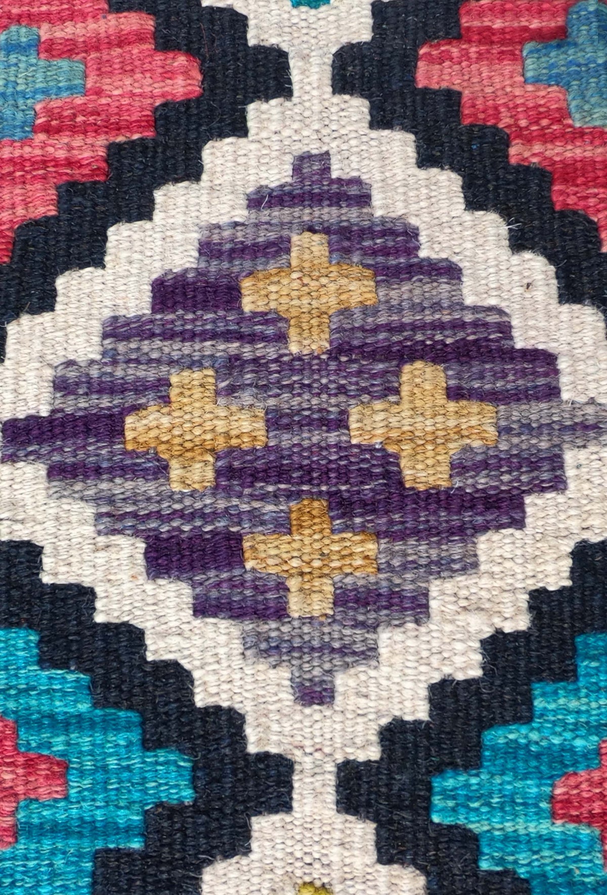 Detalle de motivos geométricos coloridos en alfombra Kelim de lana Pakistaní