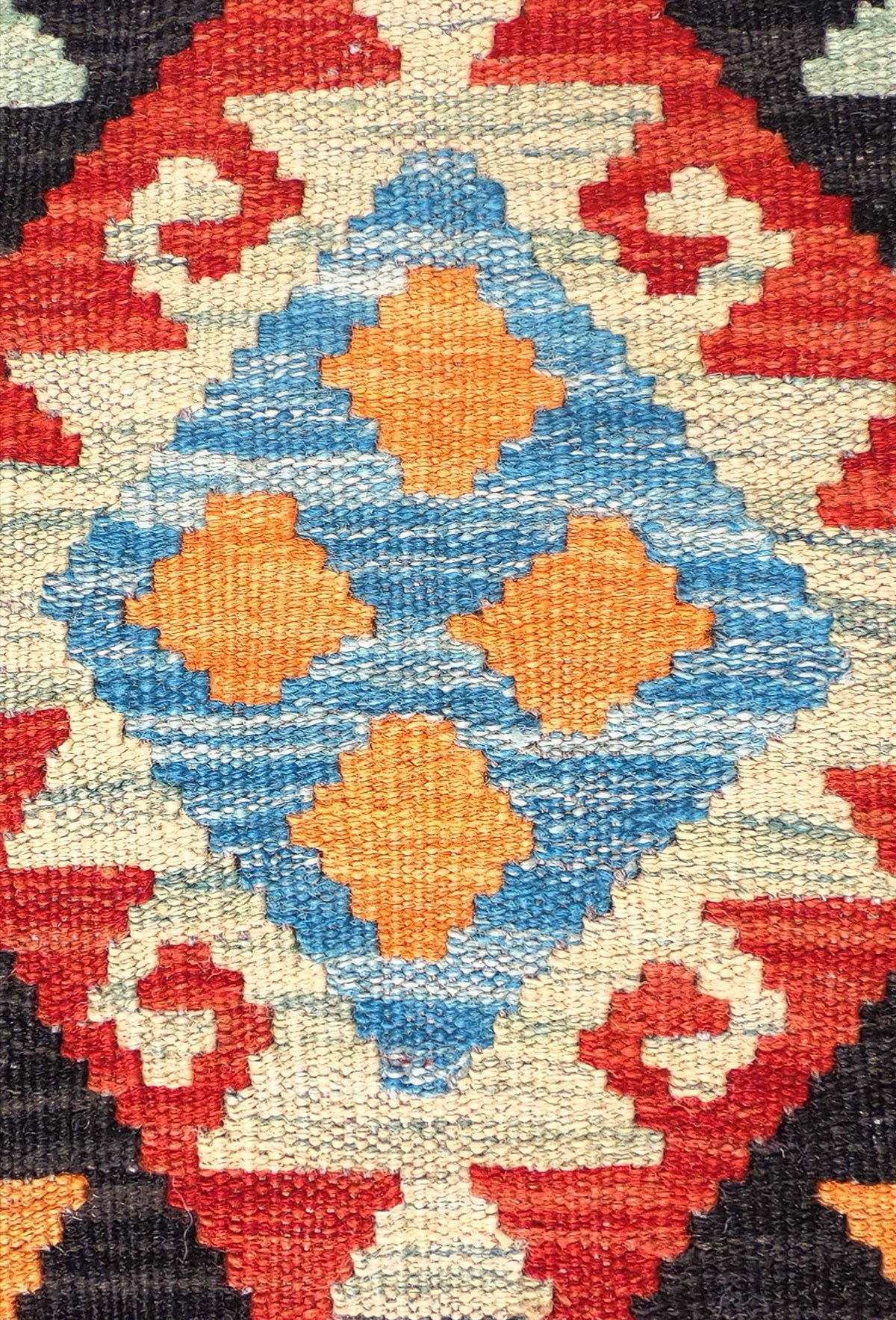 Detalle de motivos geométricos coloridos en alfombra Kelim de lana artesanal