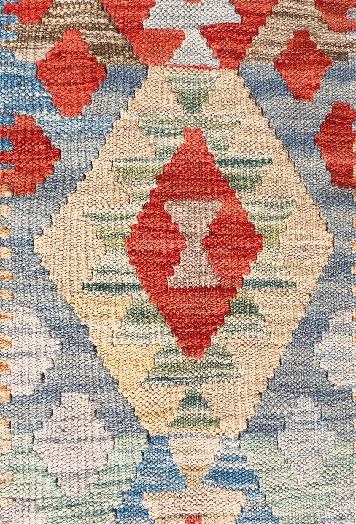Detalle de motivos geométricos coloridos en alfombra Kelim de lana pakistaní