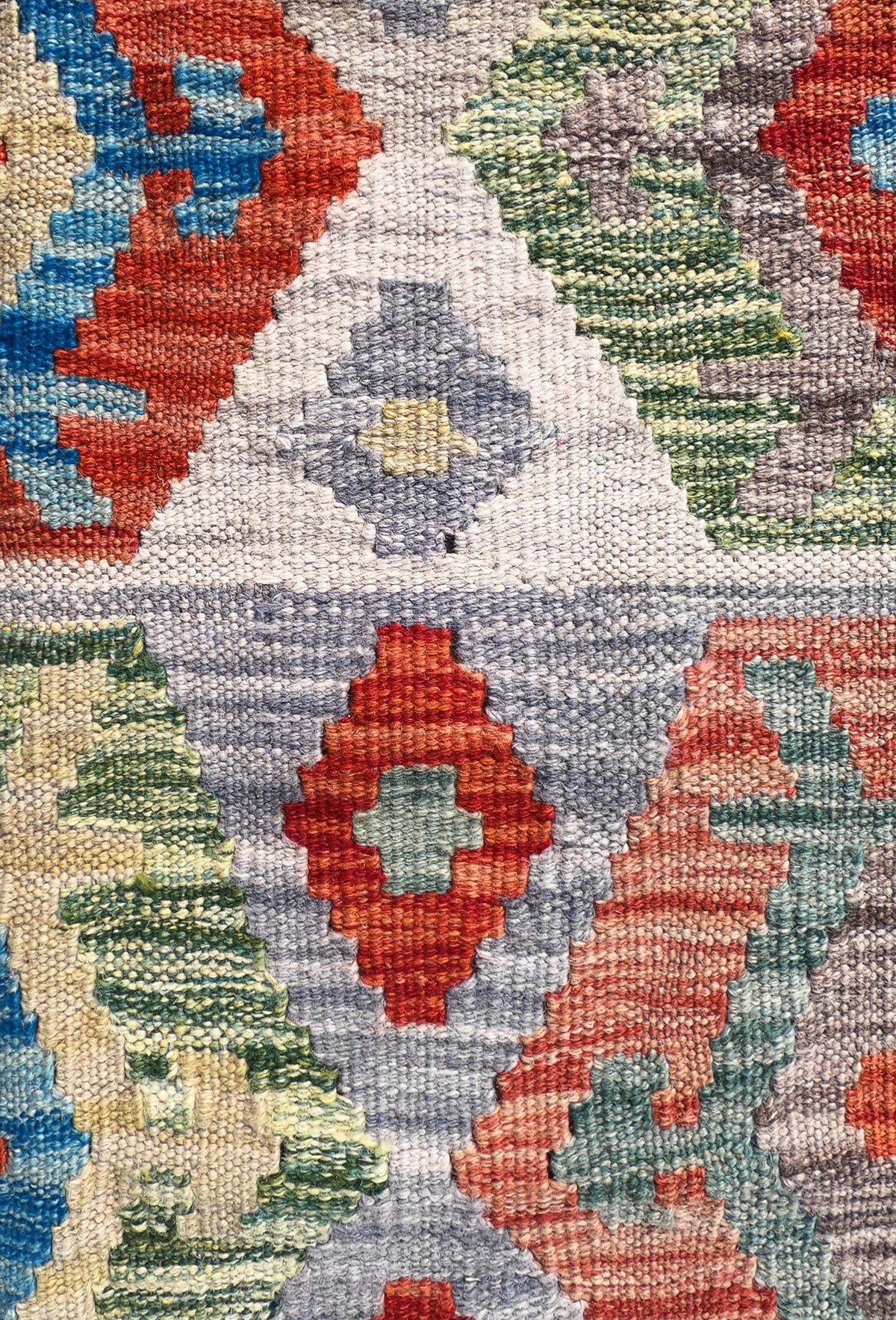 Detalle de motivos geométricos coloridos en alfombra Kelim de tejido plano
