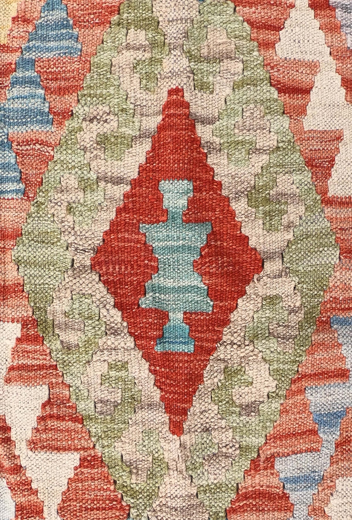 Detalle de motivos geométricos coloridos en alfombra Kelim de tejido plano