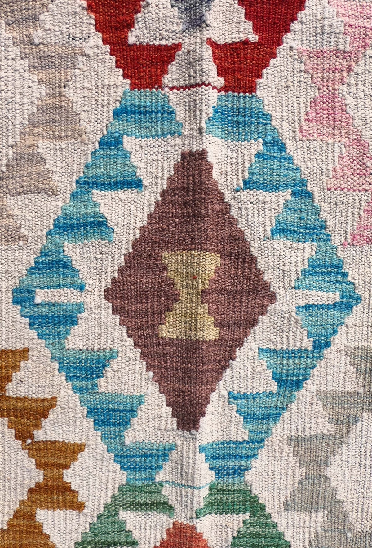 Detalle de motivos geométricos coloridos en alfombra Kelim de lana
