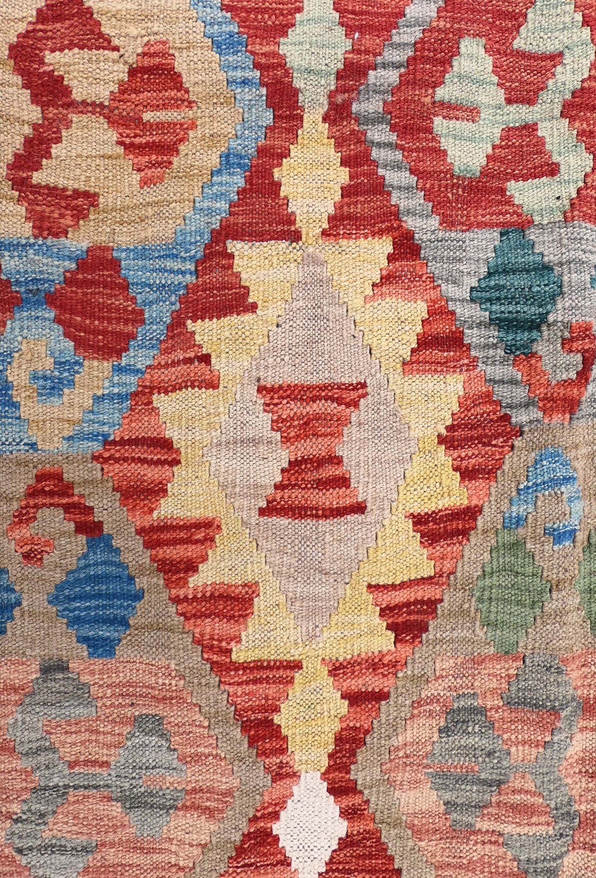 Detalle de motivos geométricos vibrantes en alfombra Kelim de lana tejida