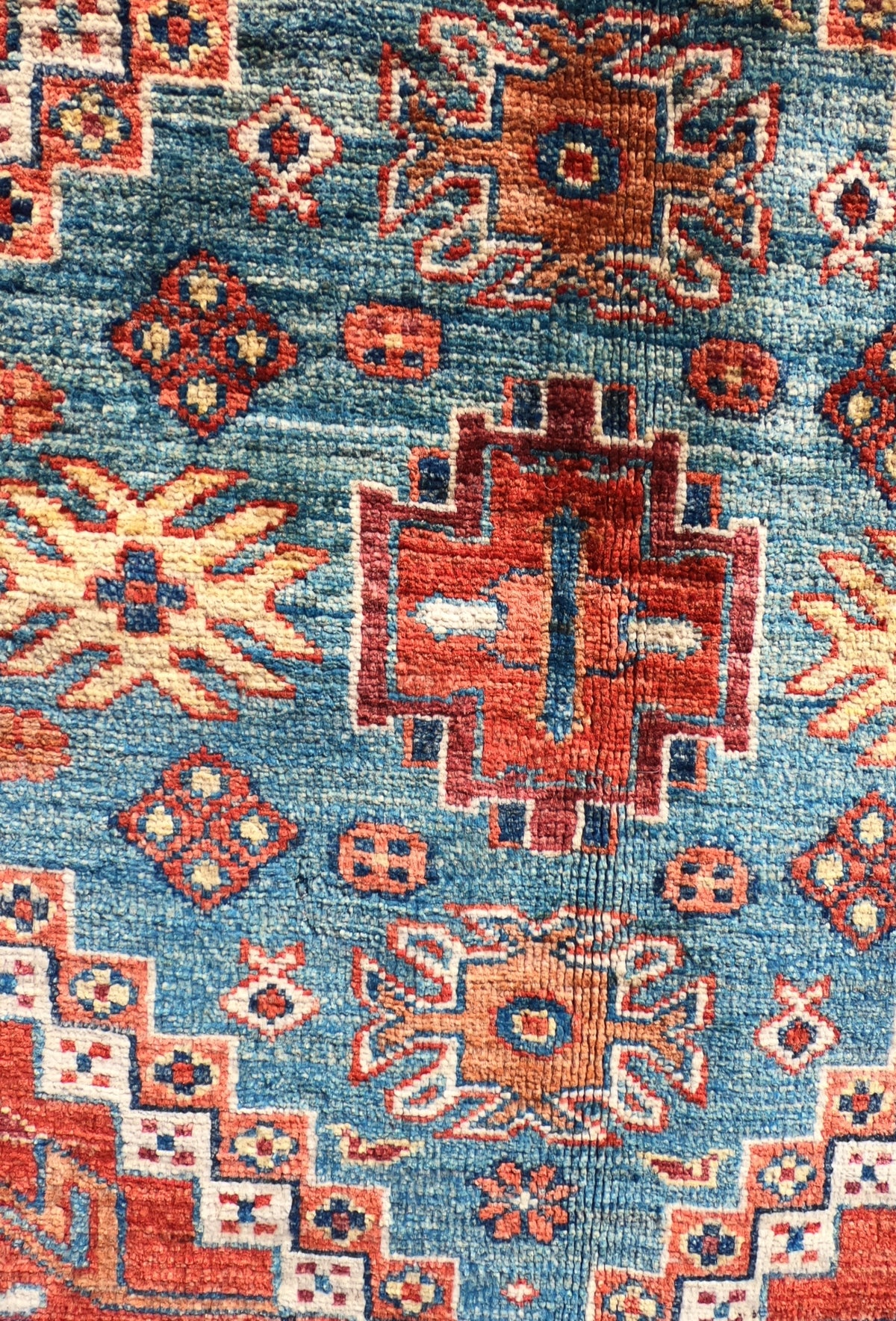 Detalle de grecas y patrón floral en alfombra persa de lana artesanal